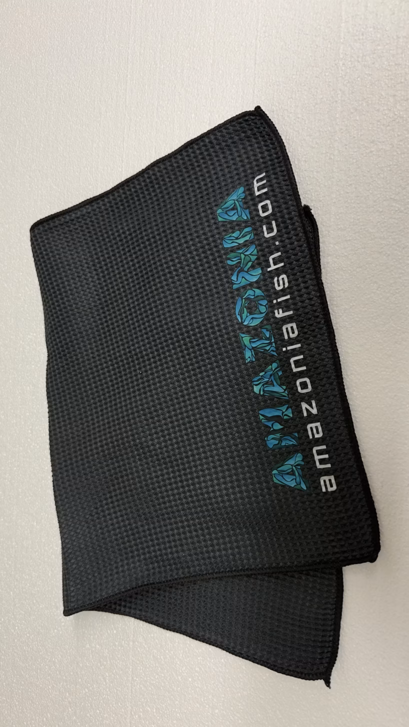 Folded black Amazonia towels with the logo along the edge